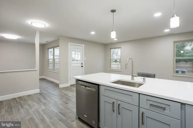 a kitchen with a sink chandelier and wooden floor
