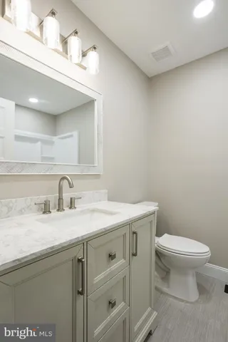 a bathroom with a granite countertop toilet sink and mirror