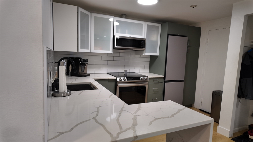 99 Cluff Crossing Road, Unit E9 Salem, NH 03079 - Photo 11 of 13 a kitchen with granite countertop a refrigerator stove and microwave