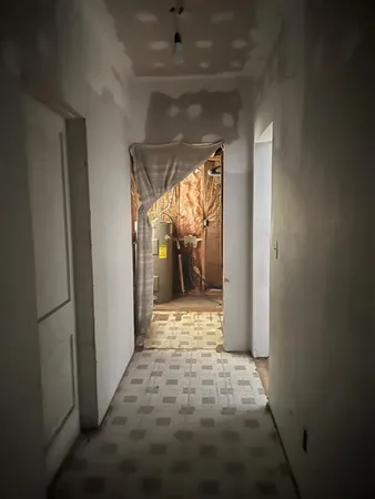 a view of a hallway with wooden floor and a bathroom