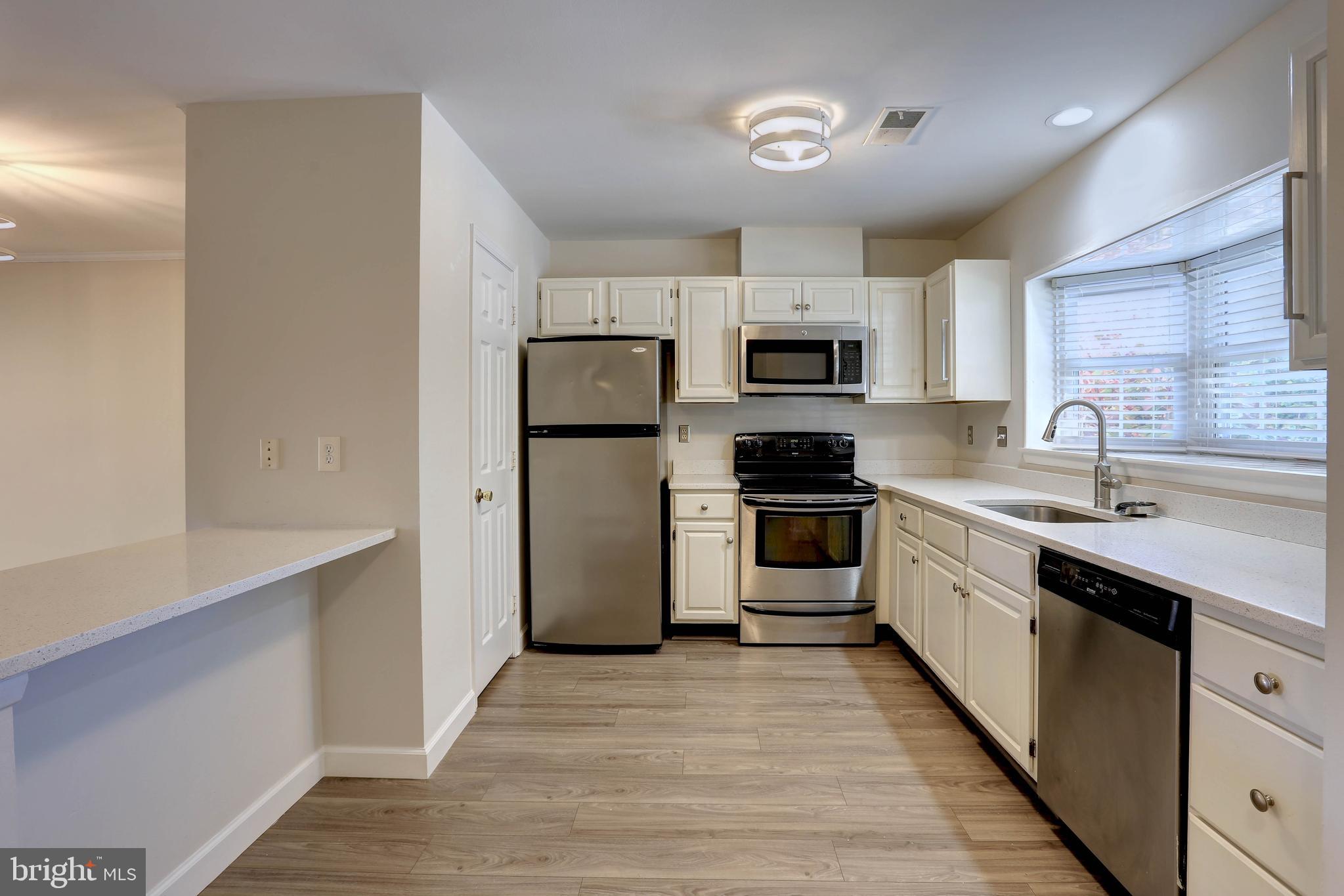 20 Bryans Mill Way Baltimore, MD 21228 - Photo 9 of 36 a kitchen with a refrigerator a stove top oven a sink and dishwasher with wooden floor