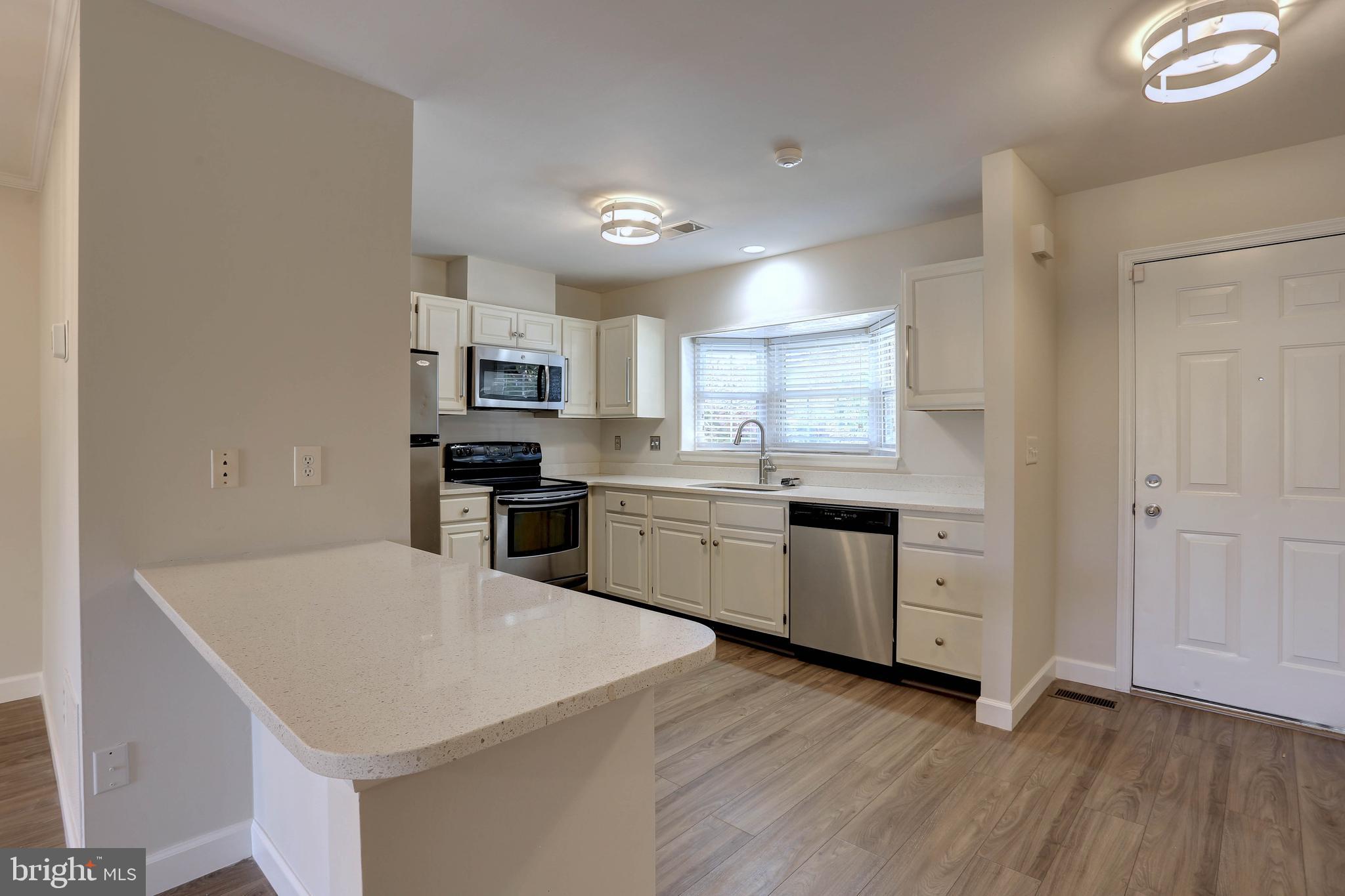 20 Bryans Mill Way Baltimore, MD 21228 - Photo 10 of 36 a kitchen with granite countertop white cabinets and white appliances