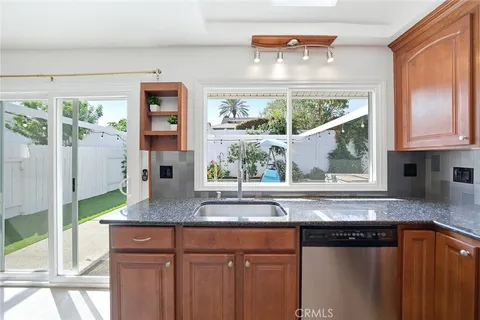 a kitchen with stainless steel appliances granite countertop a stove a sink and a granite counter tops with large windows