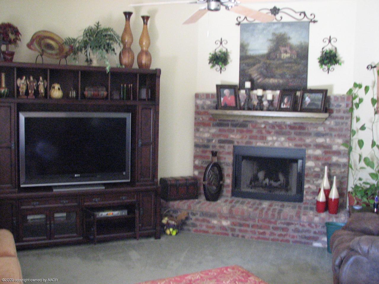 6602 Slater Circle Amarillo, TX 79110 - Photo 2 of 25 a living room with a fireplace a flat screen tv and a potted plant