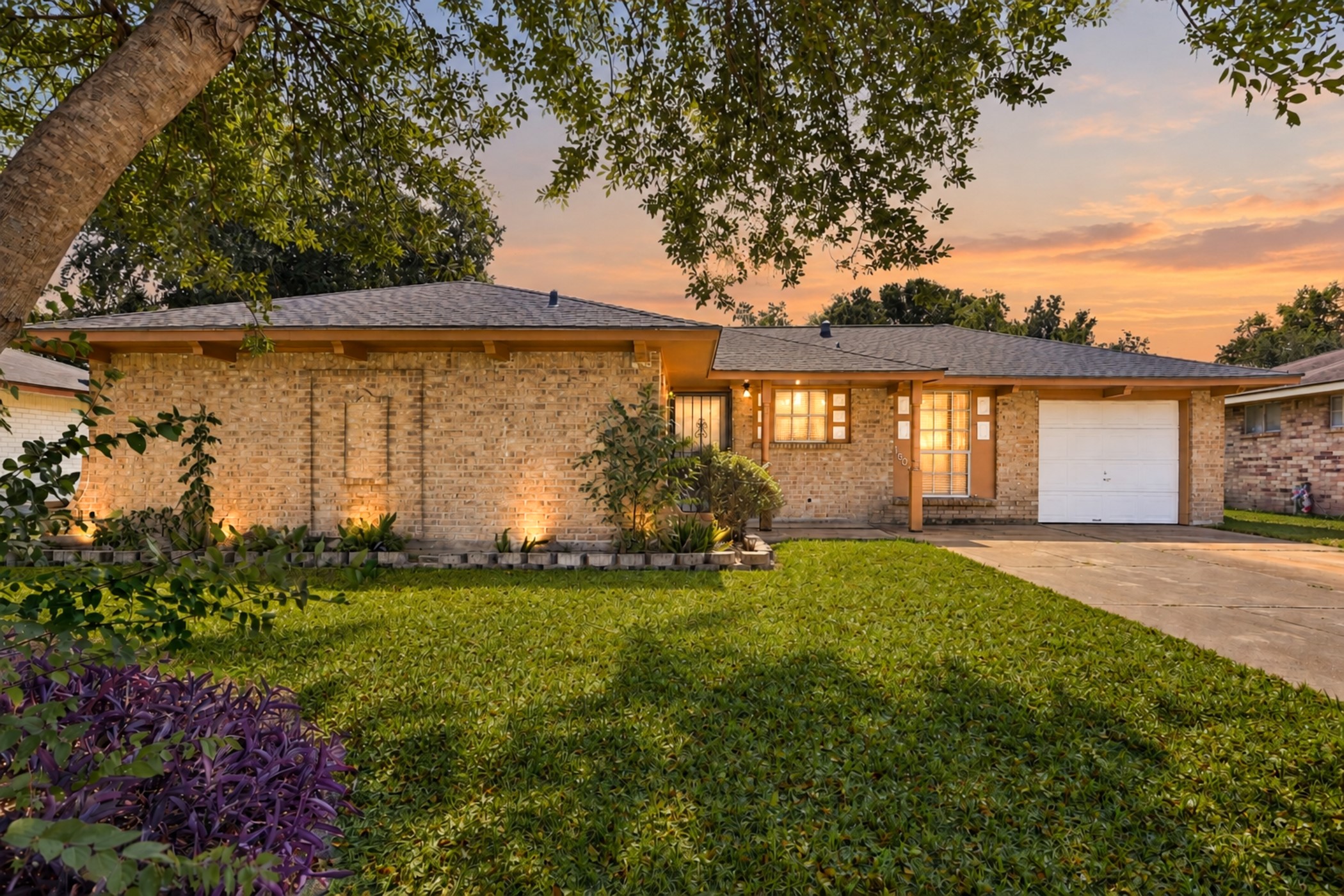 1507 Willow Rock Road Houston, TX 77088 - Photo 1 of 27 Classic single-story brick home with a mature shade tree, established landscape beds, and a one-car attached garage. Digitally enhanced twilight image; landscape lighting shown is not present on the property.