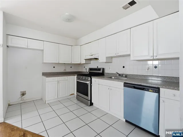 a kitchen with white cabinets stainless steel appliances and sink