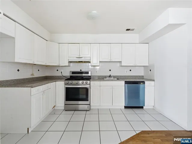 a kitchen with a sink a stove top oven and white cabinets