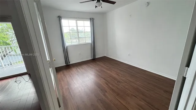 an empty room with wooden floor chandelier fan and windows