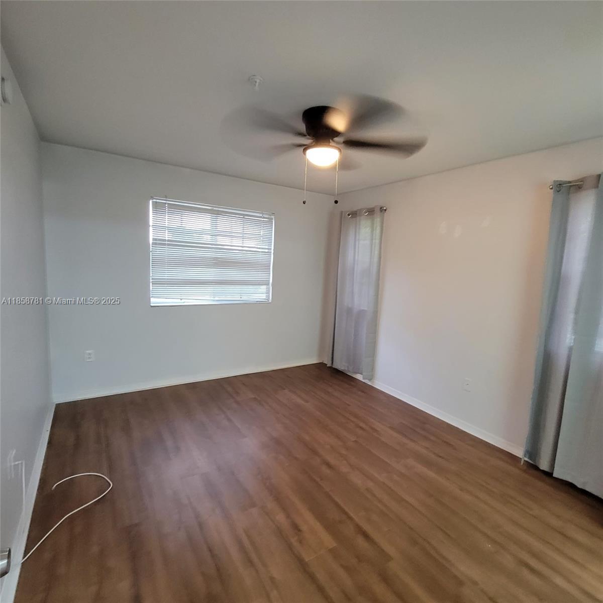711 Southwest 111th Way, Unit 3017 Pembroke Pines, FL 33025 - Photo 12 of 20 an empty room with wooden floor chandelier fan and windows