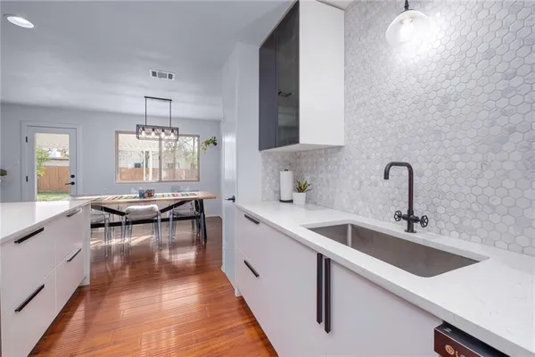 a kitchen with a sink dishwasher a dining table and chairs with wooden floor