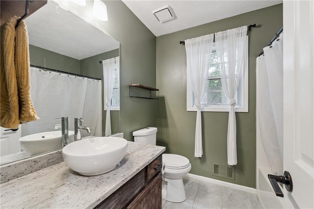 8020 Estee Drive Cumming, GA 30028 - Photo 14 of 41 a bathroom with a granite countertop sink toilet and shower