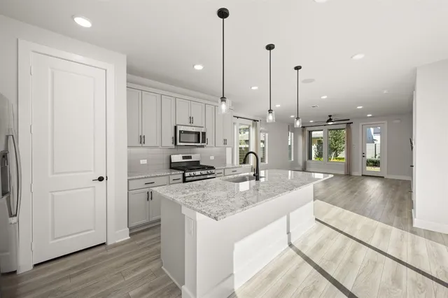 a kitchen with stainless steel appliances granite countertop a sink a stove and a wooden floor