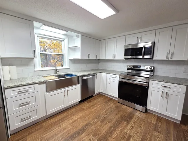 a kitchen with granite countertop cabinets stainless steel appliances and a window
