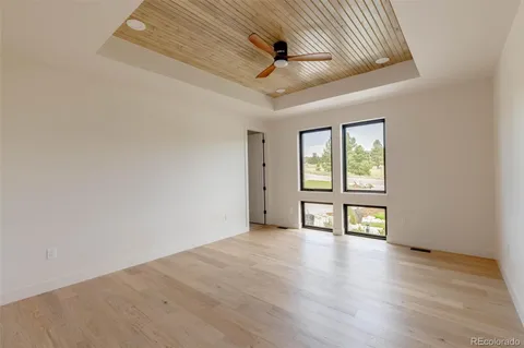 an empty room with wooden floor fan and windows