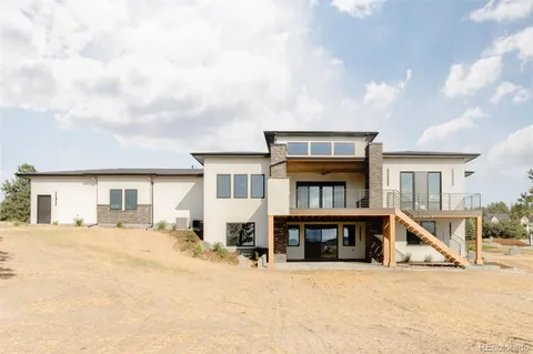a view of a house with wooden deck and a floor to ceiling window