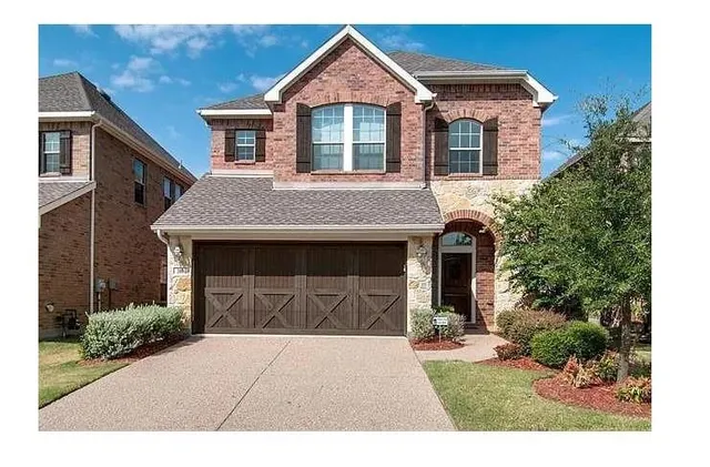 a front view of a house with a garden and trees