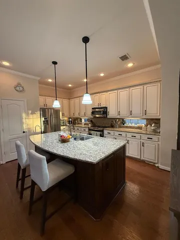 a kitchen with kitchen island granite countertop a sink a counter top space appliances and cabinets