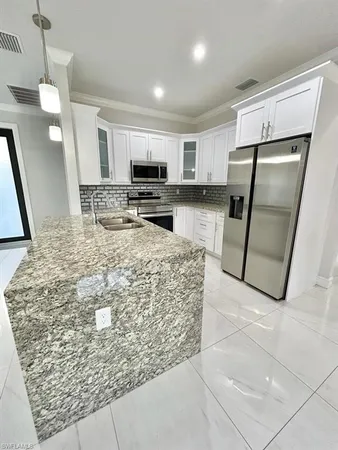 a kitchen with stainless steel appliances granite countertop a refrigerator oven a sink a stove with island and cabinets