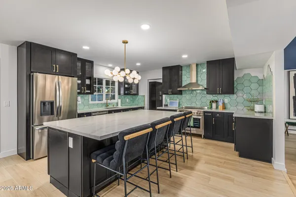 a kitchen with stainless steel appliances a dining table chairs refrigerator and microwave