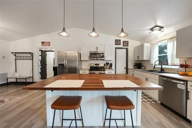 a kitchen with stainless steel appliances granite countertop a sink a stove and a refrigerator