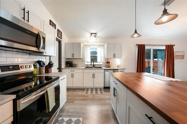 a kitchen with stainless steel appliances a dining table chairs and refrigerator