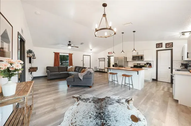 a living room with furniture kitchen view and a chandelier