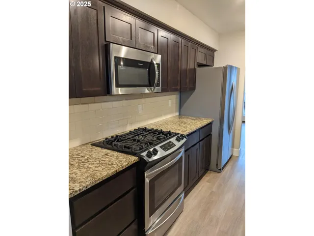 a kitchen with granite countertop stainless steel appliances and wooden cabinets