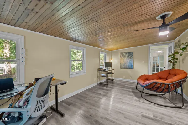a living room with stainless steel appliances furniture a clock and a view of kitchen