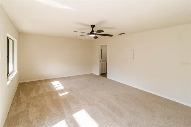 an empty room with windows and ceiling fan