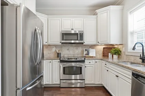 a kitchen with white cabinets and stainless steel appliances