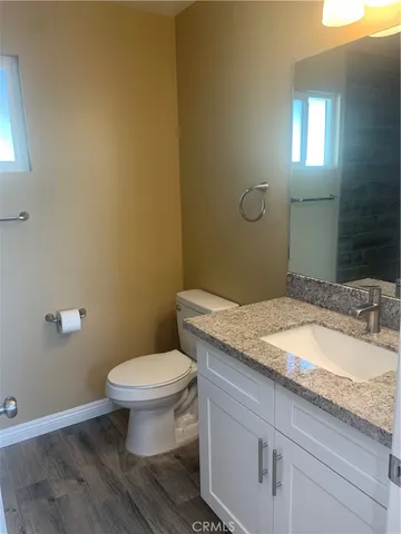 a bathroom with a granite countertop toilet a sink and mirror