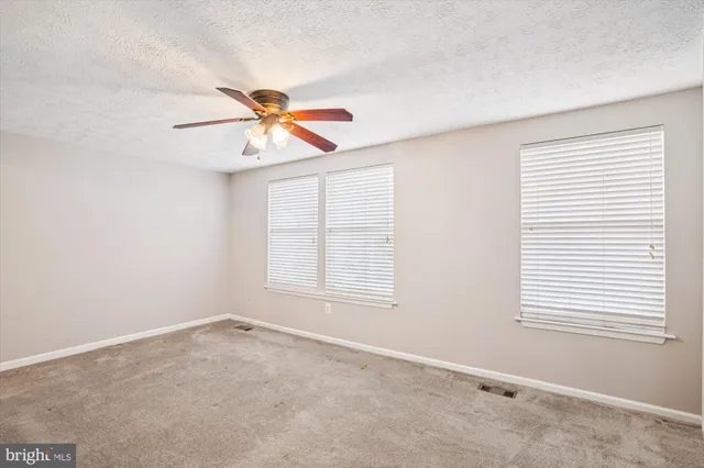 an empty room with closet and a ceiling fan