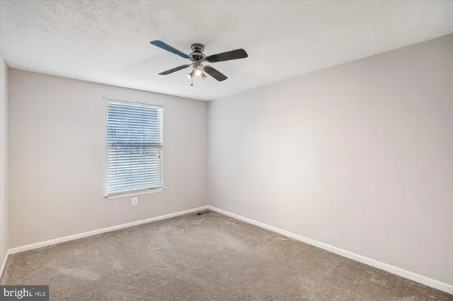 an empty room with windows and chandelier fan