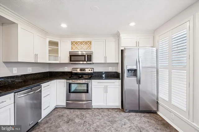 a kitchen with stainless steel appliances granite countertop a refrigerator a stove a sink and a microwave