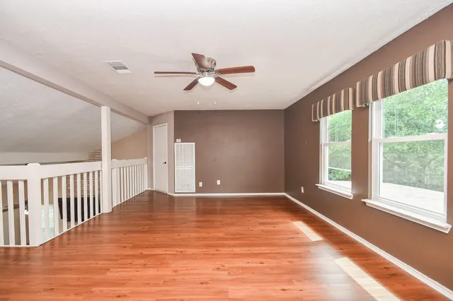 a view of an empty room with wooden floor and a window