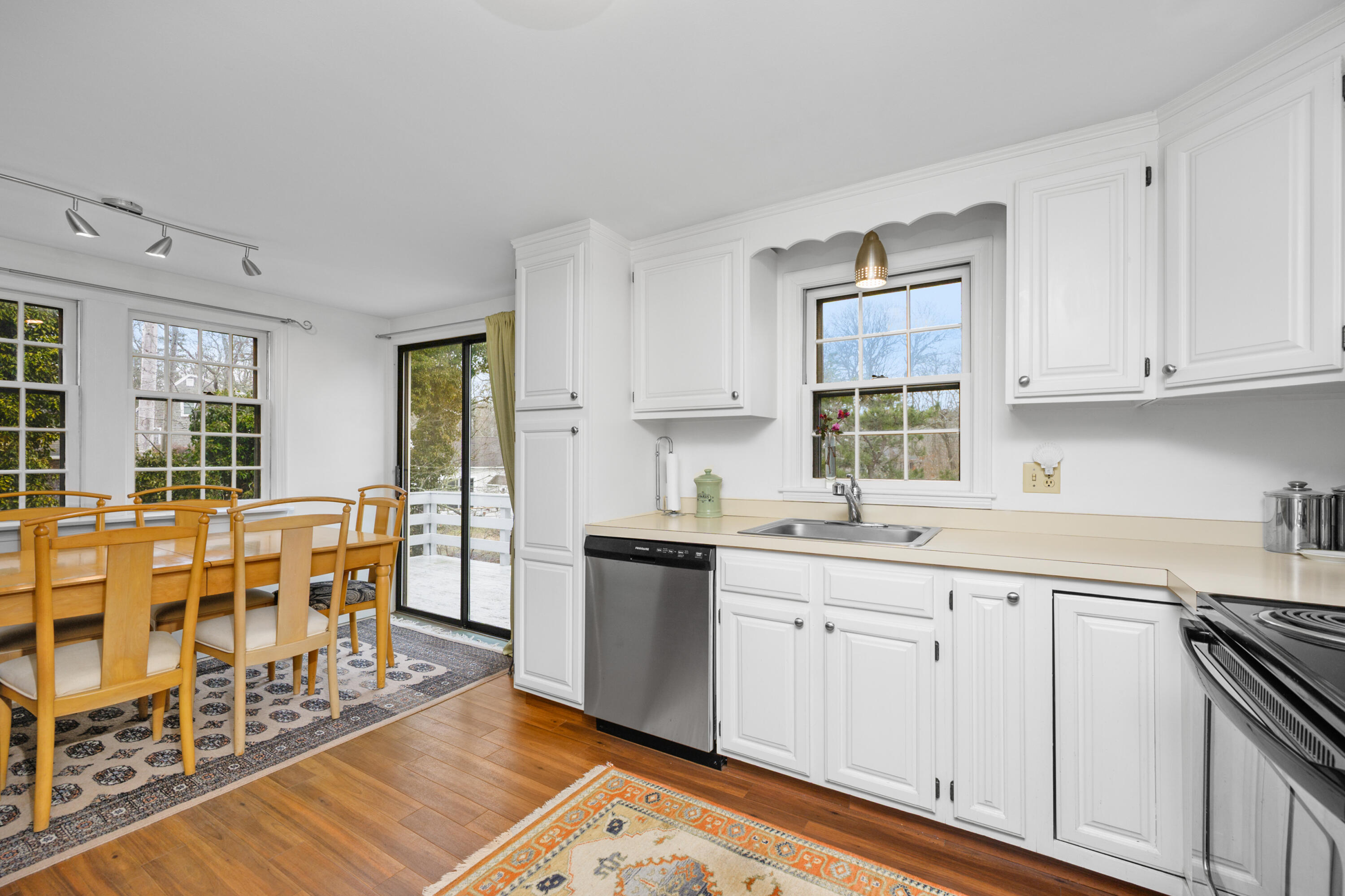 1157 Orleans-Harwich Road Harwich, MA 02645 - Photo 11 of 41 a kitchen with stainless steel appliances granite countertop a stove top oven a sink a dining table and chairs with wooden floor