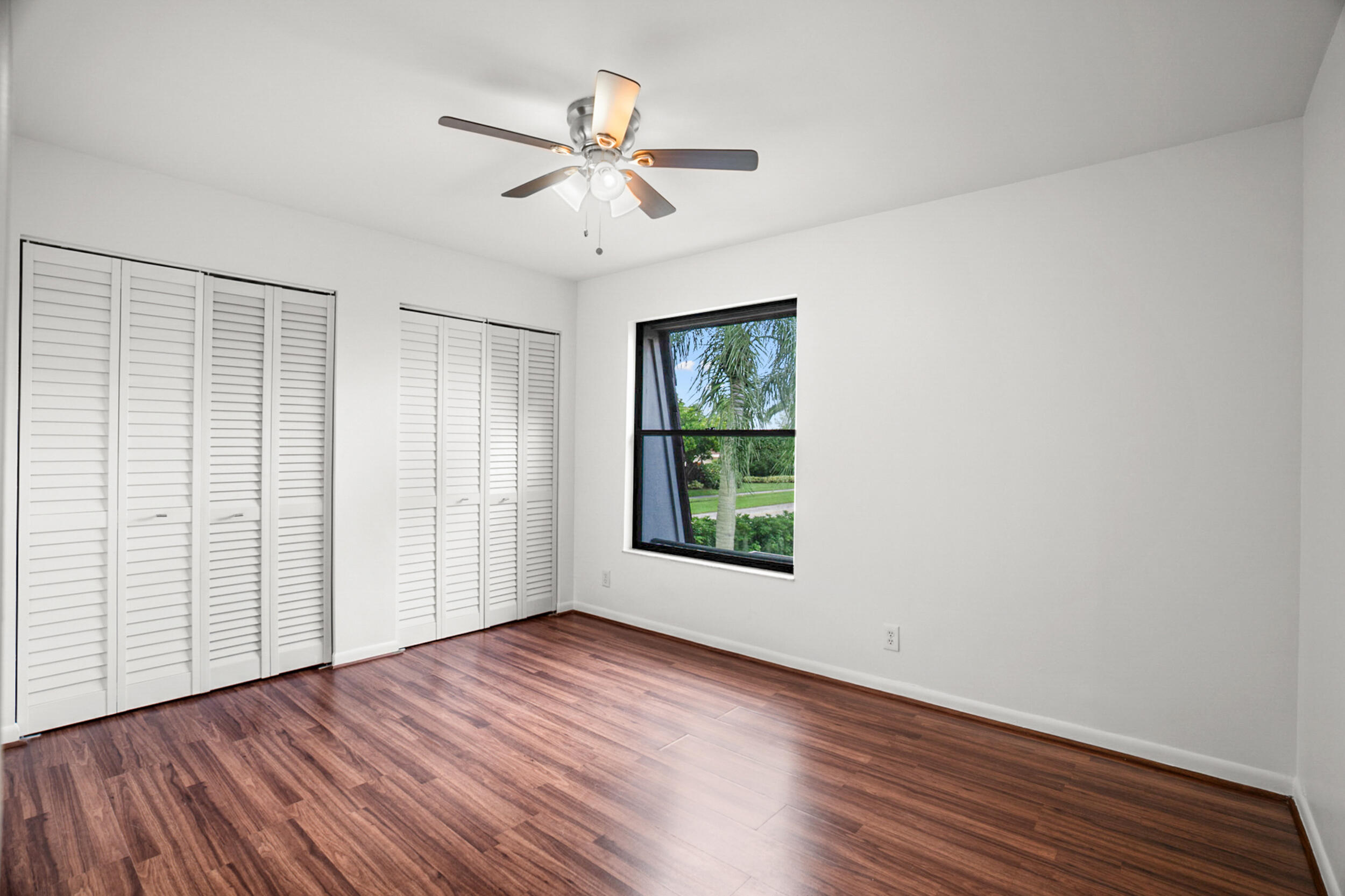7690 Courtyard Run West Boca Raton, FL 33433 - Photo 14 of 22 an empty room with wooden floor chandelier fan and windows