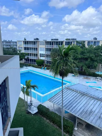 a view of a swimming pool with a yard and potted plants