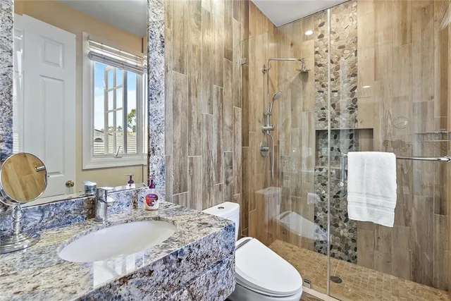 a bathroom with a granite countertop sink toilet a mirror and shower