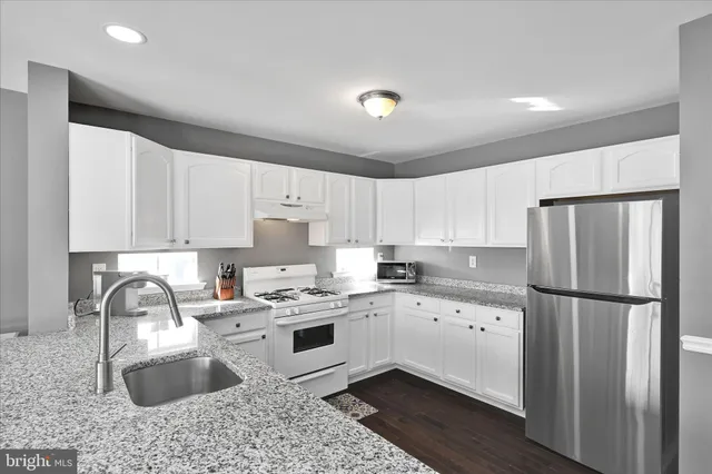 a kitchen with granite countertop a sink stove and refrigerator