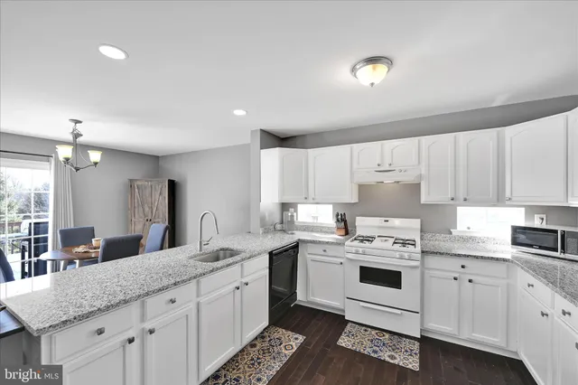 a kitchen with granite countertop a sink stainless steel appliances and white cabinets