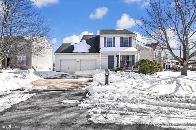 a front view of a house with a yard covered in snow