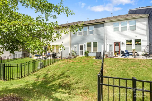 a backyard of a house with table and chairs plants and large tree