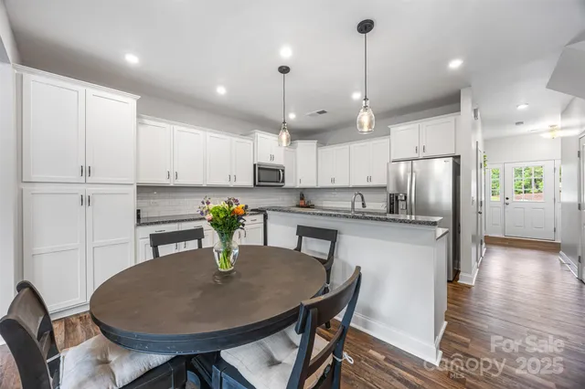 a kitchen with stainless steel appliances granite countertop a sink a stove a refrigerator cabinets and chairs