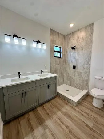 a spacious bathroom with a double vanity sink a toilet and a shower