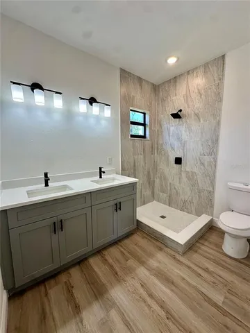 a spacious bathroom with a double vanity sink a toilet and a shower