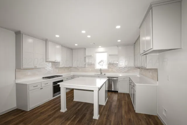 a kitchen with a sink white cabinets and wooden floor