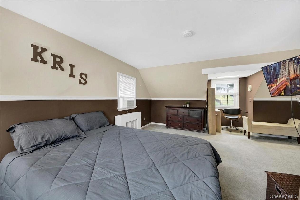 10 Susquehanna Road Ossining, NY 10562 - Photo 14 of 31 Primary bedroom on the 2nd floor with sloped ceilings and light beige walls featuring a brown wainscoting accent