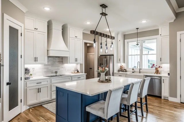 a kitchen with stainless steel appliances kitchen island granite countertop a sink a stove a refrigerator cabinets and dining table