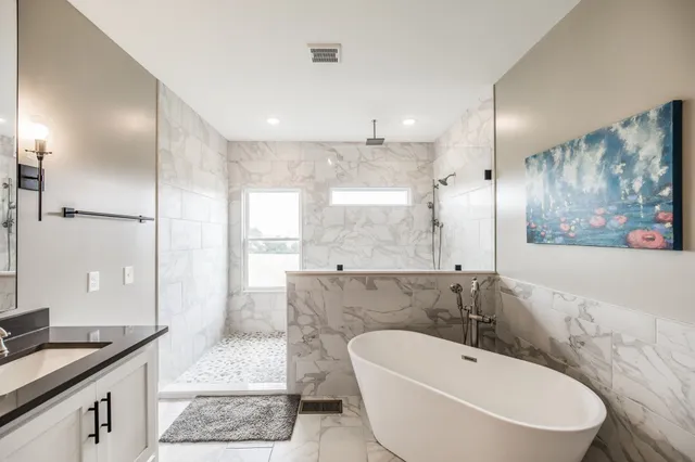 a spacious bathroom with a bathtub shower sink mirror and toilet